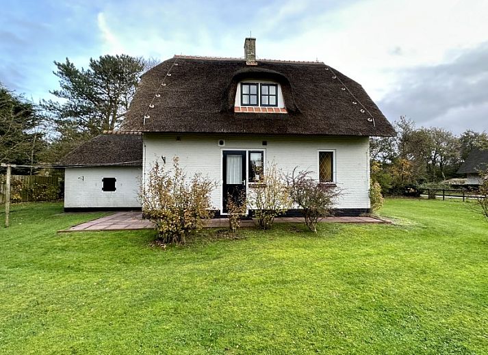 Akkerduin vakantiehuis met rieten dak in Ballum, Ameland, omgeven door groene tuin.