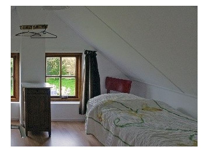 Ferienhaus Suzan in Ballum, Ameland mit charmanter roter Eingangstuer und gruenem Garten.