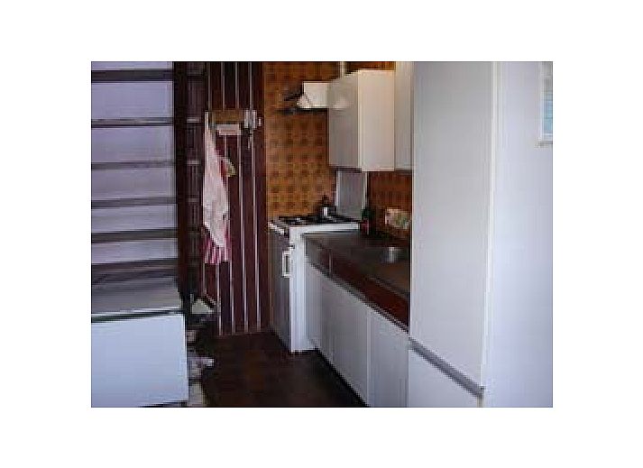 Ferienhaus Suzan in Ballum, Ameland mit charmanter roter Eingangstuer und gruenem Garten.