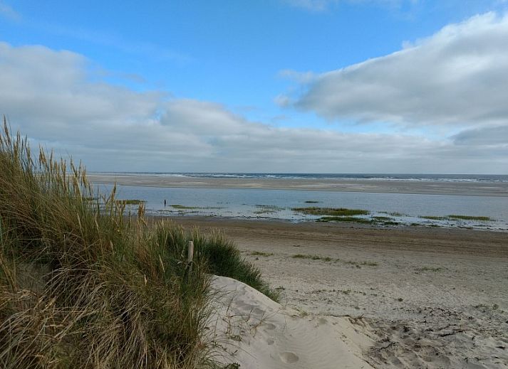 Dining area in vacation home Naar Zee, Buren, Ameland with wooden table and colorful chairs.