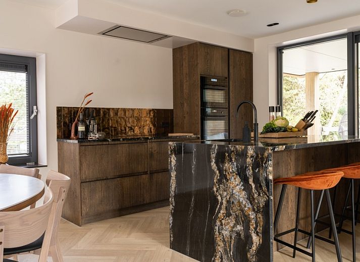 Hoofdingang van vakantiehuis MIEKIE in Buren, Ameland met houten trap en groene omgeving.