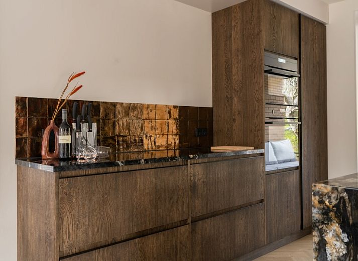 Hoofdingang van vakantiehuis MIEKIE in Buren, Ameland met houten trap en groene omgeving.