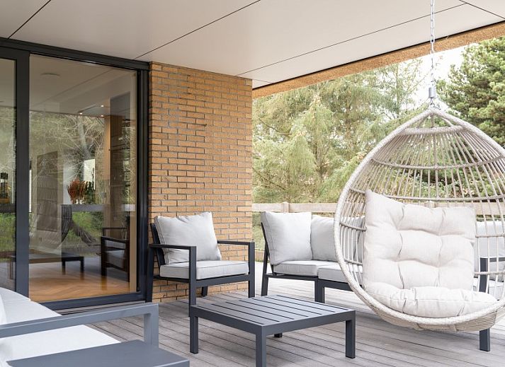 Kind speelt op trampoline bij vakantiehuis MIEKIE in Buren, Ameland, omringd door bomen.