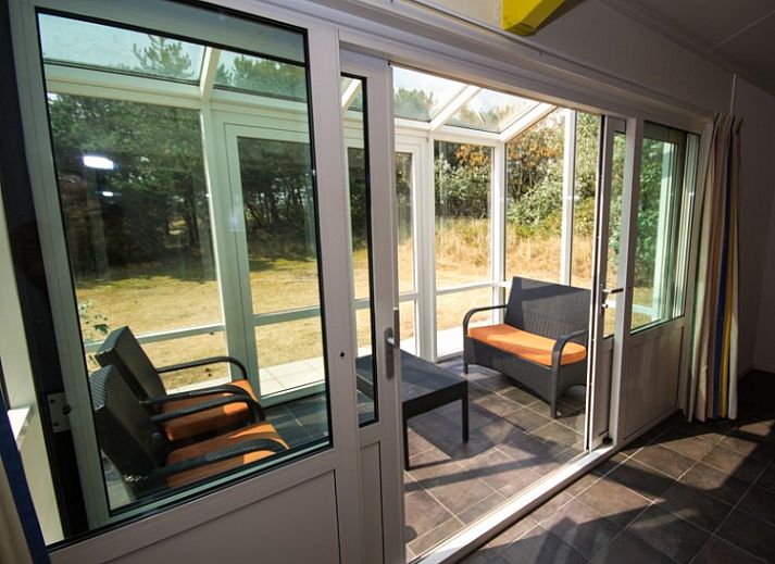 Gemtliches Wohnzimmer von Bungalow 18 in Buren, Ameland, mit bunten Mbeln und Gartenblick.