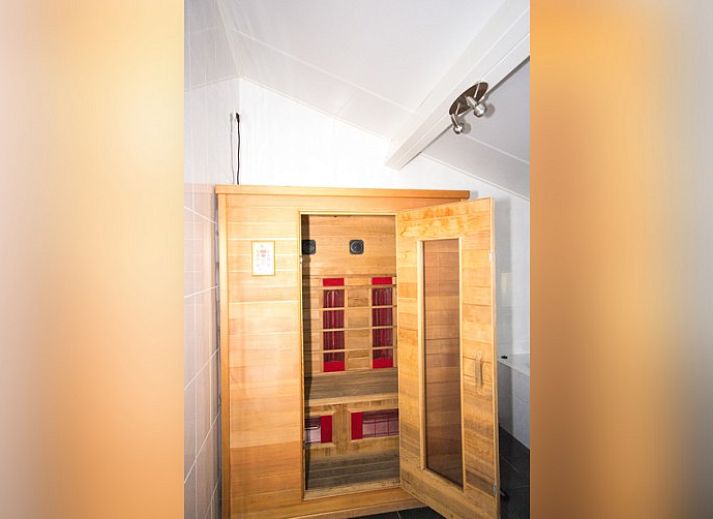 Heller Wohnbereich im Bungalow 18, Buren, Ameland mit bequemen Sitzgelegenheiten und groen Fenstern.