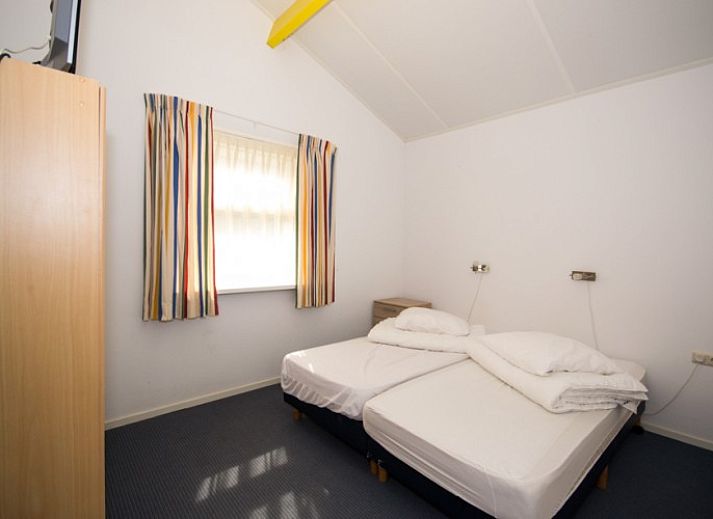 Heller Wohnbereich im Bungalow 18, Buren, Ameland mit bequemen Sitzgelegenheiten und groen Fenstern.