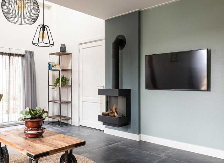 Gemuetliches Wohnzimmer in der Wohnung Dorsvloer, Hollum, Ameland, mit moderner Einrichtung und Kamin fuer einen entspannten Aufenthalt.