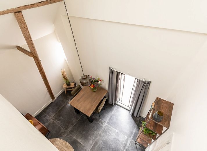 Essecke in der Unterkunft Dorsvloer, Hollum, Ameland, mit Holztisch und Blumenvase fuer eine stimmungsvolle Mahlzeit.