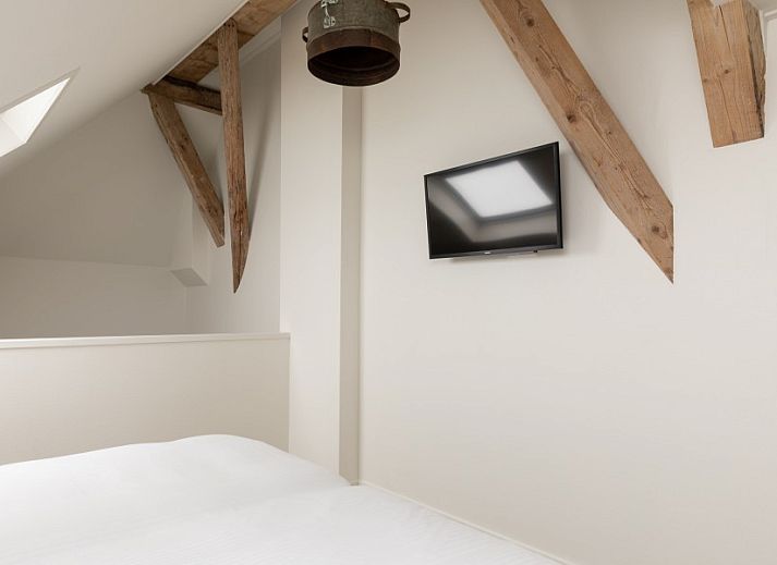 Essecke in der Unterkunft Dorsvloer, Hollum, Ameland, mit Holztisch und Blumenvase fuer eine stimmungsvolle Mahlzeit.