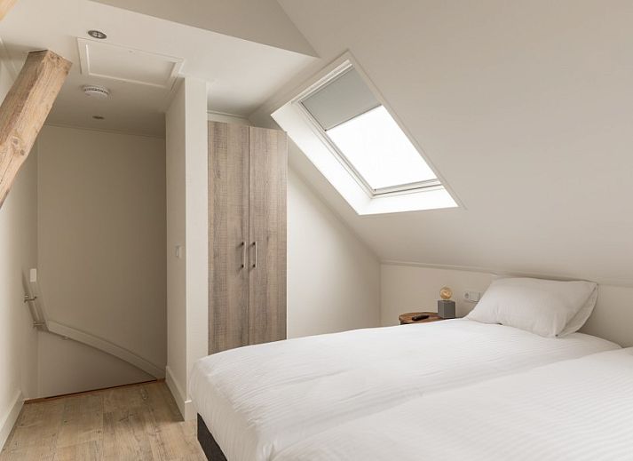 Essecke in der Unterkunft Dorsvloer, Hollum, Ameland, mit Holztisch und Blumenvase fuer eine stimmungsvolle Mahlzeit.