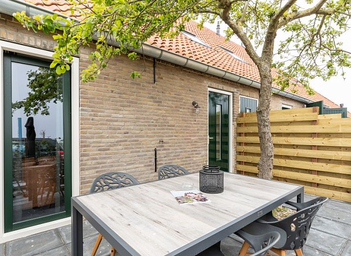 Moderne Essecke in der Wohnung Dorsvloer, Hollum, Ameland, mit Industrielampe und bunten Blumen.