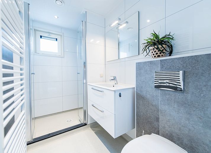 Gemuetliches Wohnzimmer von Waddenlodge 6+2, einem Ferienhaus in Hollum, Ameland. Helle Einrichtung mit bequemen Sitzgelegenheiten und viel natuerlichem Licht.