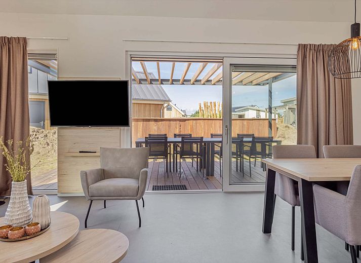 Gerumige Terrasse des Ferienhauses in Hollum, Ameland, mit berdachung und Gartenmbeln.