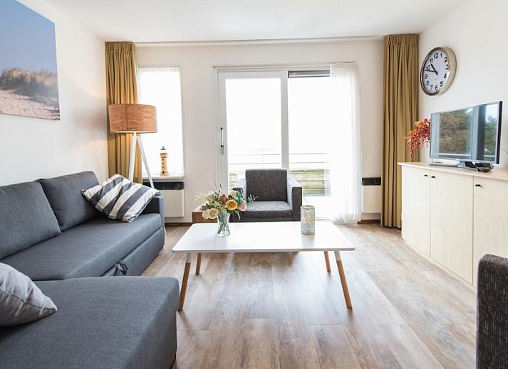 Gezellige woonkamer in appartement Zilverschoon, Hollum, Ameland met comfortabele zitruimte en uitzicht op terras.
