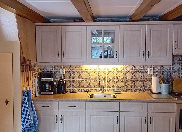 Gemuetliches Wohnzimmer im Ferienhaus Anno 1618, Hollum, Ameland mit Holzeinrichtung und bequemen Sitzgelegenheiten.