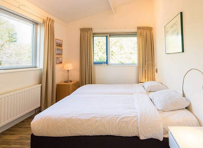 Gezellige woonkamer van Vijverwoning 4, een bungalow in Hollum, Ameland, met veel natuurlijk licht en uitzicht op de groene omgeving.