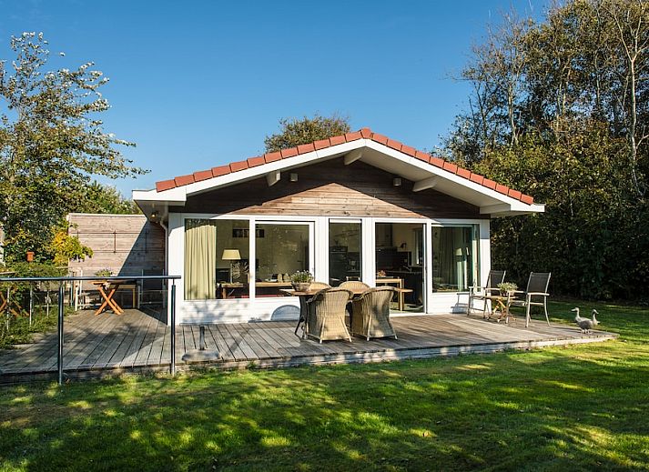 Gezellige woonkamer van Vijverwoning 4, een bungalow in Hollum, Ameland, met veel natuurlijk licht en uitzicht op de groene omgeving.