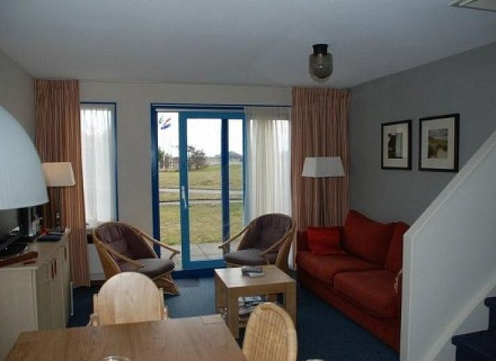 Gemtliches Wohnzimmer in Amelander Kaap Nr. 54, Hollum, Ameland mit rotem Sofa und moderner Einrichtung.