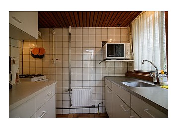 Charmantes Ferienhaus Schier in Schiermonnikoog, Watteninseln, umgeben von grnen Hecken.