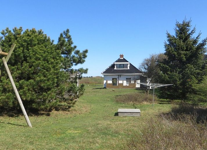 Zeerust-Ferienhaus in Schiermonnikoog mit Blick auf den Leuchtturm und die gruene Umgebung.