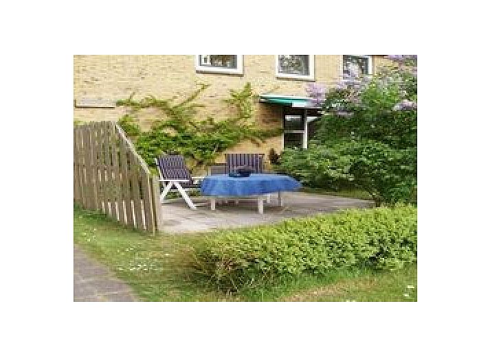 Genieen Sie die sonnige Veranda des Ferienhauses Kia-Ora auf Schiermonnikoog mit bequemen Sitzgelegenheiten und grner Umgebung.