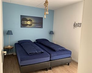 Slaapkamer in La Guitarra vakantiehuis De Cocksdorp Texel met tweepersoonsbed en blauwe accenten.