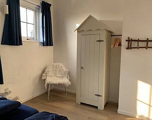 La Guitarra De Cocksdorp Texel, slaapkamer met houten kast en gezellige stoel.