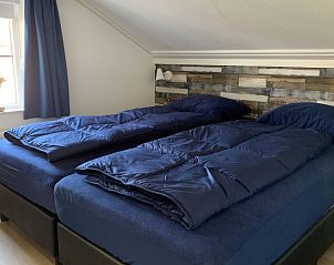 Gezellige slaapkamer in La Guitarra vakantiehuis De Cocksdorp Texel met houten muurdecor.