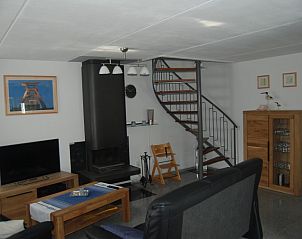 Gezellige woonkamer in De Krim 641 vakantiehuis, De Cocksdorp Texel met houtkachel en trap.