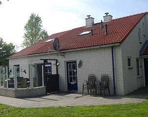 Achtertuin van De Krim 641 vakantiehuis in De Cocksdorp Texel met terras en stoelen.