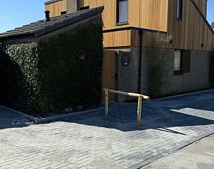 Ingang van Vakantiehuis aan de golfbaan, De Cocksdorp Texel, Waddeneilanden, met bestrate oprit en houten gevel.