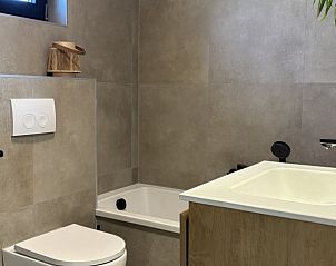 Moderne badkamer in Vakantiehuis aan de golfbaan, De Cocksdorp Texel, Waddeneilanden, met ligbad en toilet.