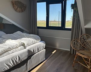 Slaapkamer met uitzicht in Vakantiehuis aan de golfbaan, De Cocksdorp Texel, Waddeneilanden, met comfortabele bedden.