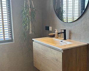 Stijlvolle badkamer met wastafel in Vakantiehuis aan de golfbaan, De Cocksdorp Texel, Waddeneilanden, met ronde spiegel.