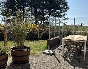 Terras met eettafel in Vakantiehuis aan de golfbaan, De Cocksdorp Texel, Waddeneilanden, omgeven door groen.