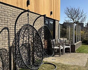 Tuin met hangstoelen bij Vakantiehuis aan de golfbaan, De Cocksdorp Texel, Waddeneilanden, met houten gevel.