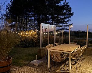 Verlicht terras in de avond bij Vakantiehuis aan de golfbaan, De Cocksdorp Texel, Waddeneilanden, met gezellige sfeer.
