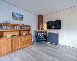 Modernes Wohnzimmer des Ferienhauses Slufterhoek 044, De Cocksdorp Texel, mit Flachbildfernseher und einladender Leseecke.