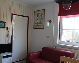 Knusse woonkamer in Onder de vuurtoren 113 vakantiehuis De Cocksdorp Texel met comfortabele bank en decoratieve kunst.