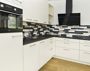 Vollstndig ausgestattete Kche im Ferienhaus De Postschipper auf Texel mit bunten Fliesen.