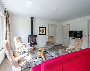 Cozy living room in Holiday home Slufterhoek 174, De Cocksdorp, Texel, with comfortable chairs and a cozy fireplace.