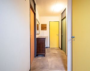 Gang met kleurrijke deuren in Vakantiehuis Slufterhoek 118, De Cocksdorp, Texel, leidt naar slaapkamers.