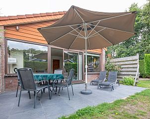 Enjoy the terrace at Holiday home Slufterhoek 102 in De Cocksdorp, Texel with comfortable chairs and a large parasol.
