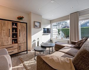 Relax in the cozy living room of Holiday home Slufterhoek 102, De Cocksdorp, Texel with a spacious sofa and lots of natural light.