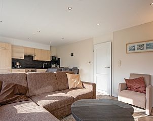 Open living space in Holiday home Slufterhoek 102, De Cocksdorp, Texel with a comfortable sitting area and view of the kitchen.