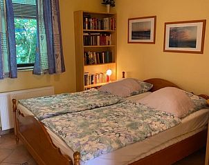 Schlafzimmer im Ferienhaus Slufterhoek 128, De Cocksdorp Texel, mit Doppelbett und Bcherregal.