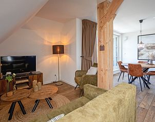 Sfeervolle woonkamer in Appartement C, De Cocksdorp, Texel met tv en zachte verlichting.