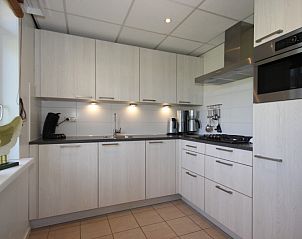 Moderne keuken in Bungalow De Witte Hoek 6 Pers., De Cocksdorp, Texel met strakke witte kastjes en inbouwapparatuur.