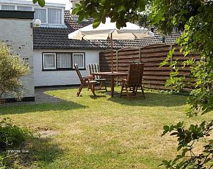 Sunny terrace in the garden of Kikkertstraat 067, De Cocksdorp, Texel, with parasol and seating.