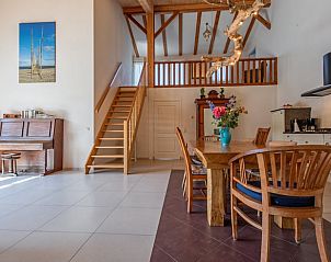 Open kitchen and dining area in Cottage in De Cocksdorp, Texel, with wooden stairs upstairs.